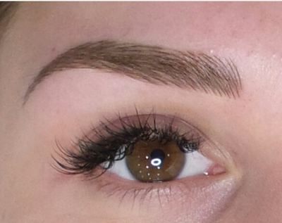 Close-up of a soft microbladed brow and volume lashes on one eye