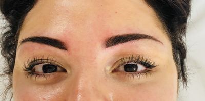 Bold brushed-up dark brows and lifted lashes on a smiling client